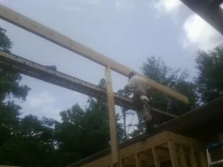 Carpenter setting a ridge beam over a new addition frame — Ice Dam Removal by Roofing Brothers in Logandale