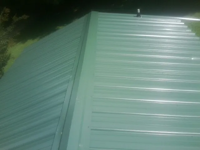 New green metal panels meeting at the ridge of a roof — Flat Roof Repair work by our crew in Logandale