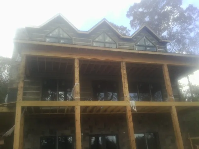 Dormers and porch framing on a large log home under construction — Roof Coating work by our crew in Logandale