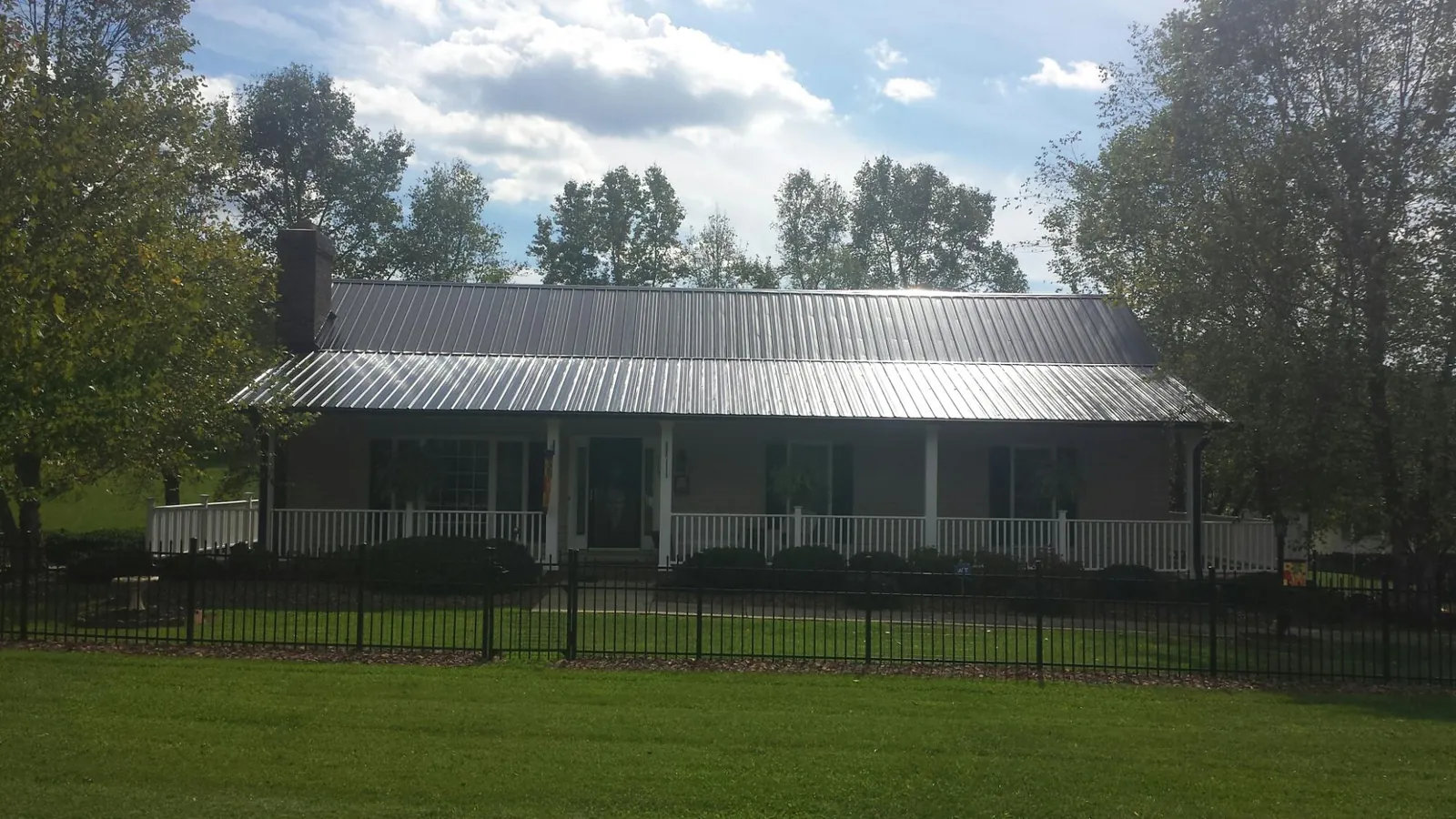 Gray metal roof on a brick ranch with a full width front porch — Gutter Guard Installation work by our crew in Logandale