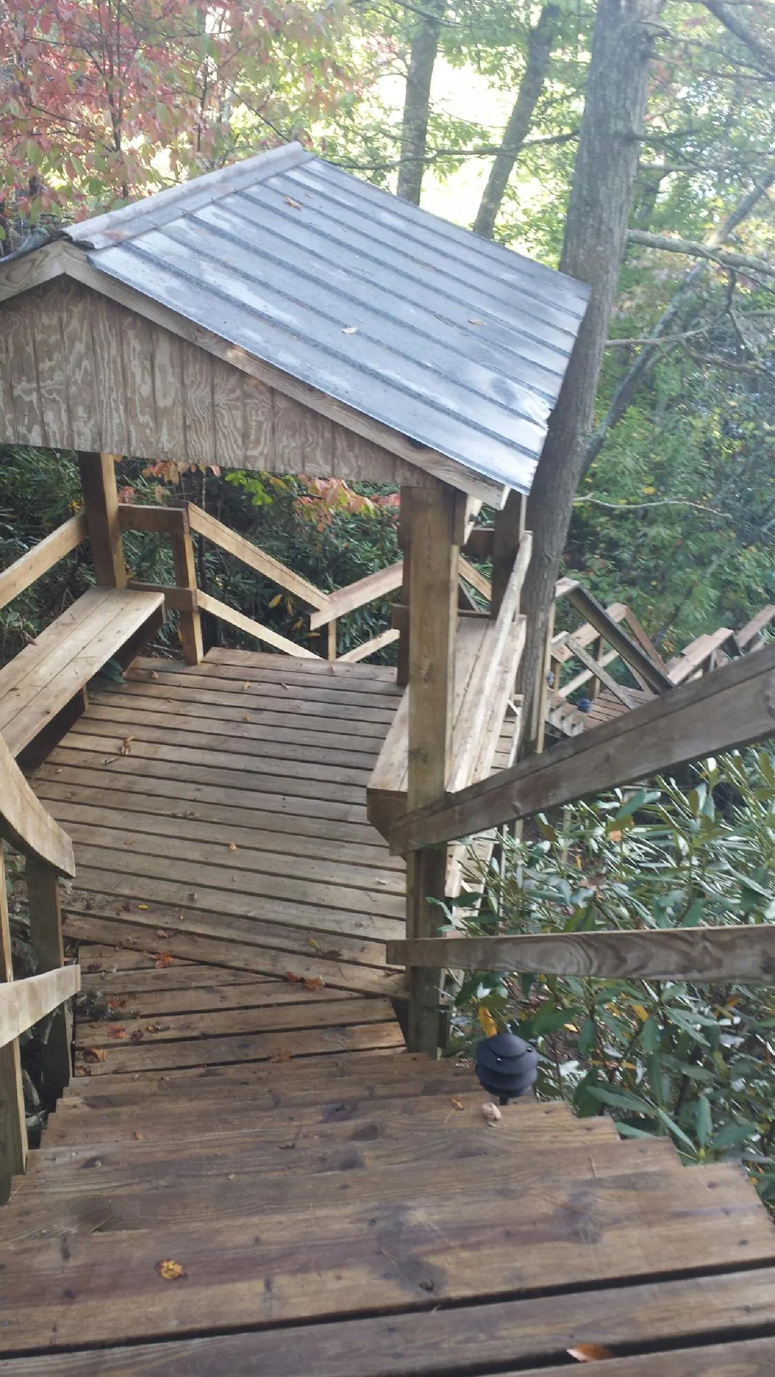 Metal roofed shelter over wooden steps on a wooded walkway — Skylight Repair & Installation work by our crew in Logandale