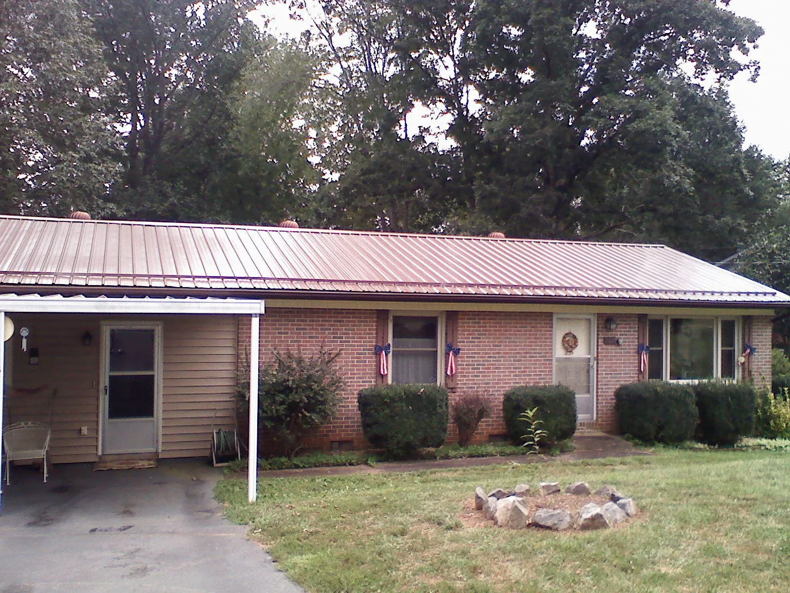 Bronze metal roof and carport on a brick ranch home — Roof Repair work by our crew in Logandale