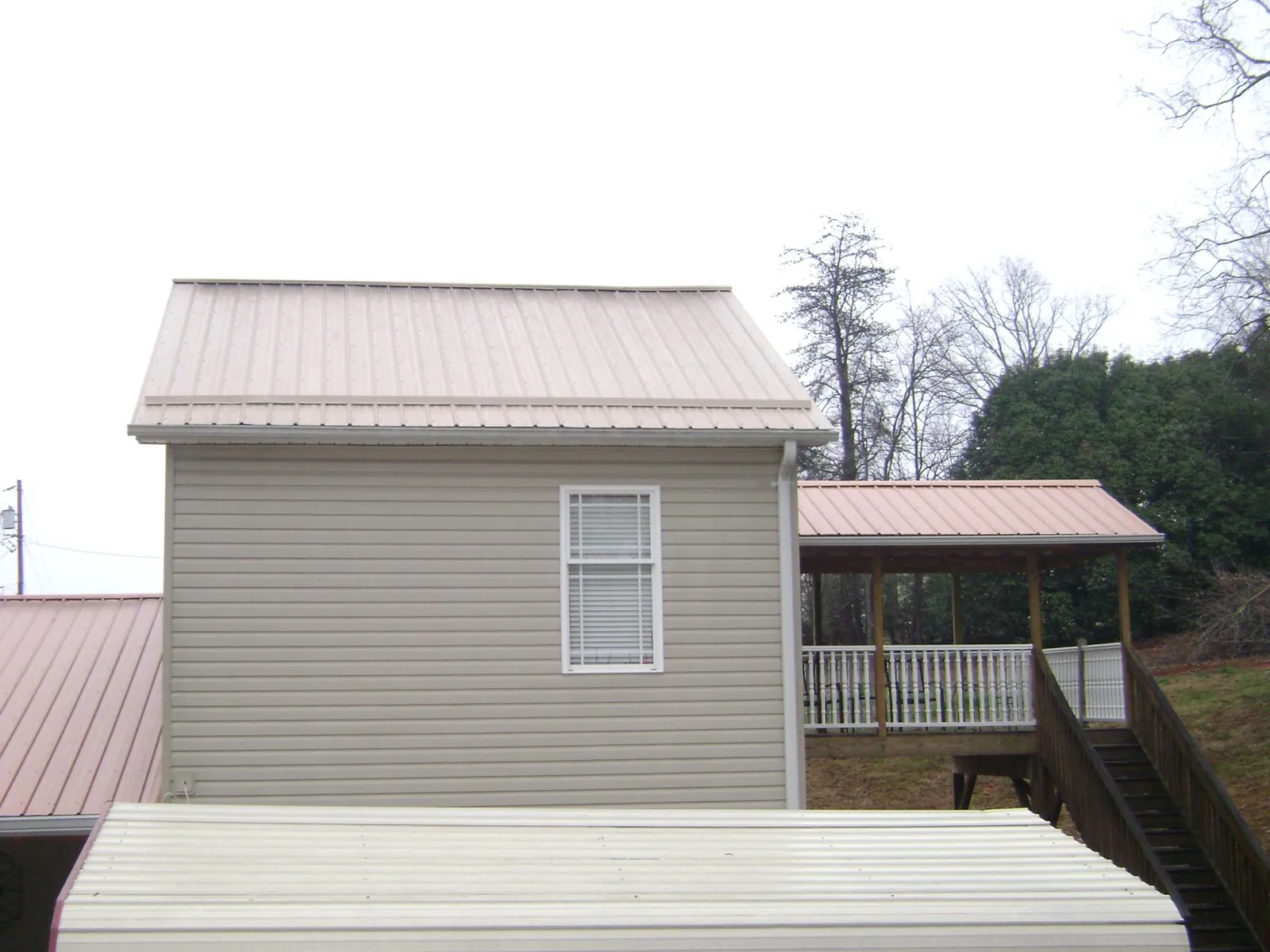 Tan metal roofs on a two story addition and attached porch, from a Roof Replacement job in Logandale